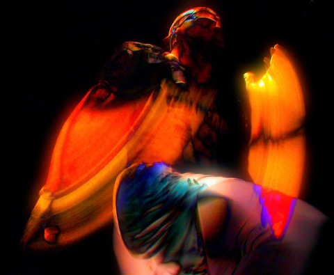 Long-exposure abstract of a dancer smeared into orange and teal light against black.